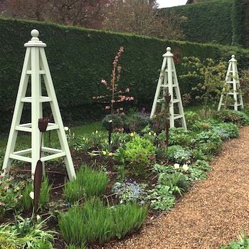 3 Large wooden garden obelisk painted Vert de Terre by Farrow and Ball in flower border.