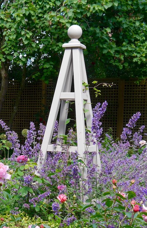 Painted wooden obelisk in garden with Salvia, Lavender and Roses