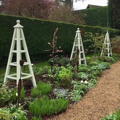 Large wooden garden obelisks painted Vert de Terre, 205cm tall with roses set within beautiful flower borders
